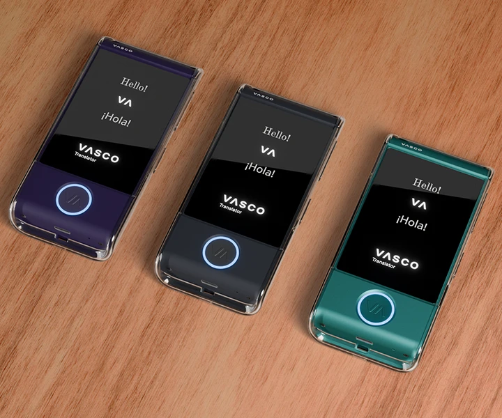 Três dispositivos Vasco Translator M4 pousados sobre uma mesa, dentro de capas de silicone transparentes em três cores diferentes, com os ecrãs ligados a exibir o logótipo da Vasco e botões LED iluminados.