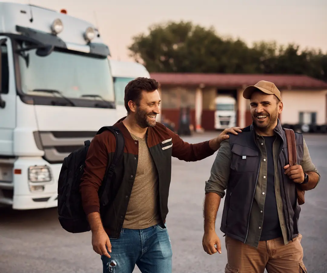 dois homens de bom humor num parque de estacionamento afastam-se dos camiões estacionados ao fundo